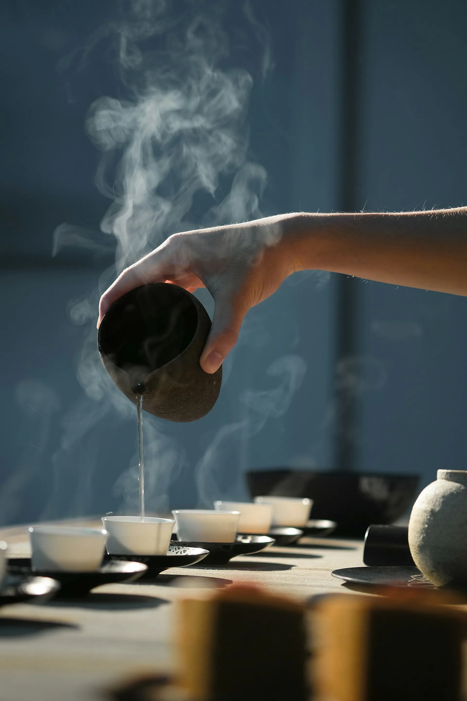 Tea being poured into small white cups